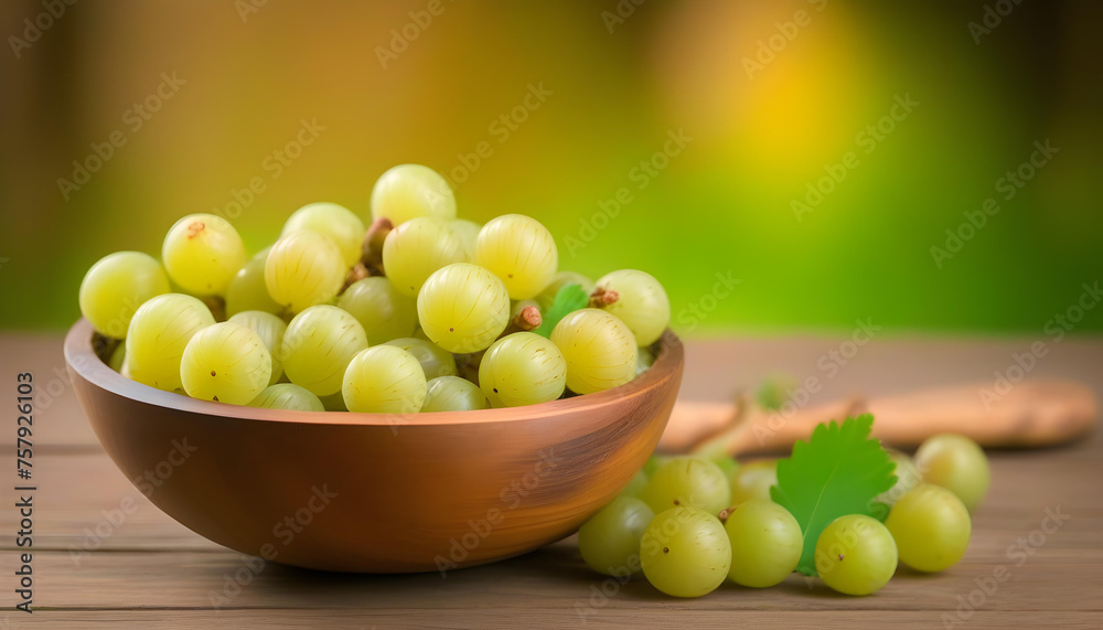 A wooden bowl filled with Indian gooseberries on a colorful or wooden background A wooden bowl filled with Indian gooseberries on a colorful or wooden background