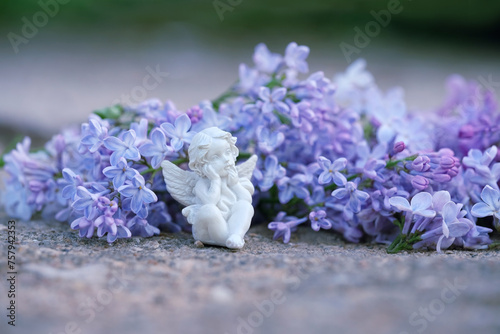 Cute angel figurine and spring lilac flowers close up, abstract natural background. Spring season. Easter holiday. symbol of faith in God, gentle romantic love