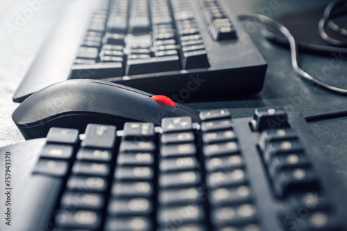 Mouse with red scrolling wheel between keyboards on office desk photo