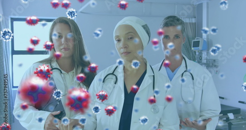 Image of a medical staff team in hospital with coronavirus cells floating on the foreground