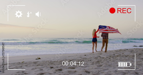 Young couple runs with US flag on beach, captured on a camera in 4k.