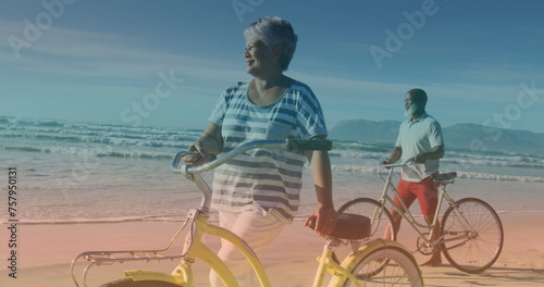 Spots of light against african american senior couple with bicycles walking together at the beach