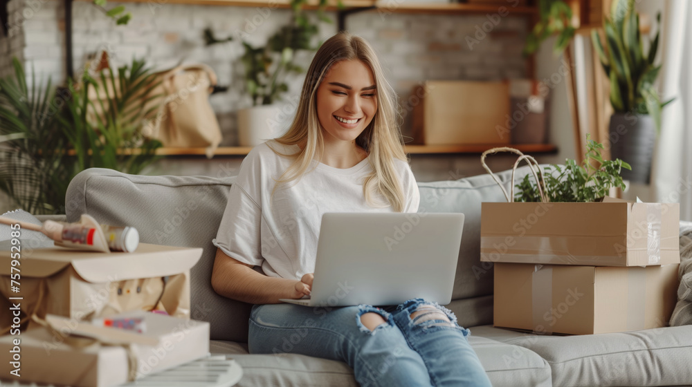 Beautiful young smiling girl working on laptop at home on couch next to cardboard boxes. Online shopping order, online shopping, online stores, delivery of goods Beautiful young smiling girl working on laptop at home on couch next to cardboard boxes. Online shopping order, online shopping, online stores, delivery of goods