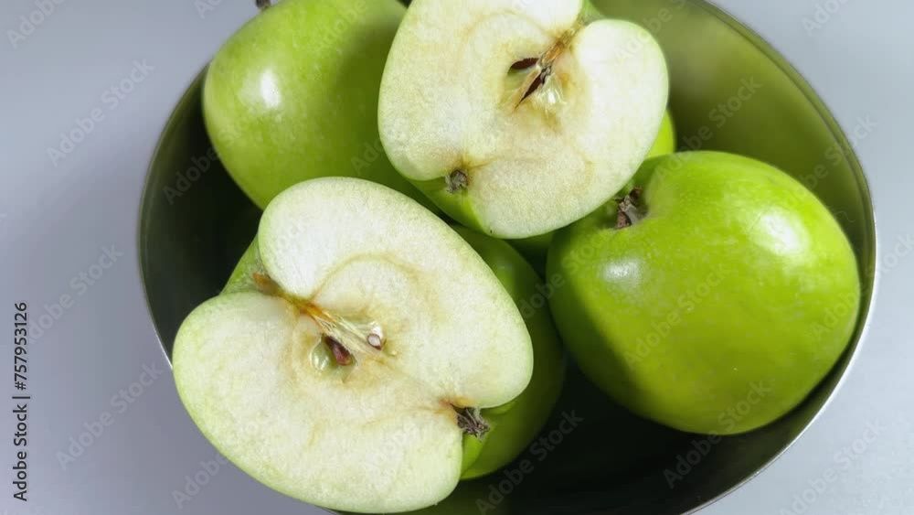 Two halves and whole green apples in stainless steel bowl Two halves and whole green apples in stainless steel bowl