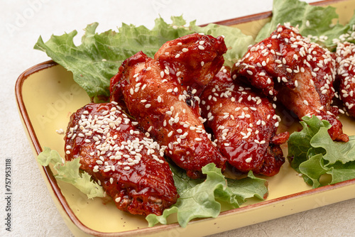 Portion of cooked chicken wings in sauce and sesame seeds