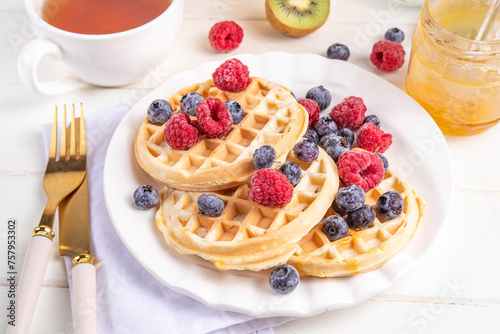 Homemade belgian waffles with summer berries and honey on white wooden table, Delicious brunch or breakfast belgian waffles