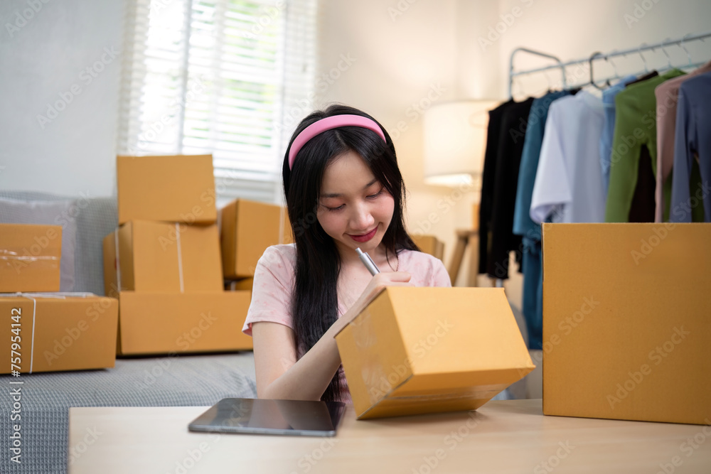 Asian woman small business entrepreneur working from home use tablet for commercial inspection. online marketing Packaging box, concept ecommerce Asian woman small business entrepreneur working from home use tablet for commercial inspection. online marketing Packaging box, concept ecommerce