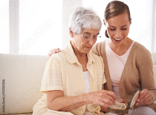 Senior woman, mother and daughter with gift for bonding, appreciation and love relaxing on sofa at home, living room and apartment. Female people, family or looking at jewelry for pearl heirloom