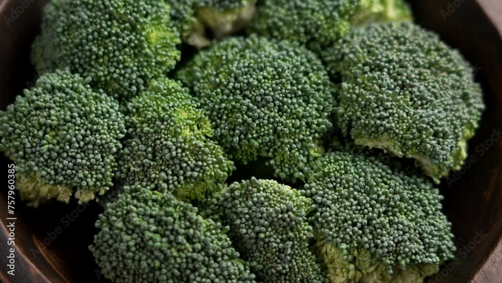 Many fresh broccoli cut pieces in a rustic wooden bowl. Cooking green natural vegetable meal. Top view. Rotation Many fresh broccoli cut pieces in a rustic wooden bowl. Cooking green natural vegetable meal. Top view. Rotation
