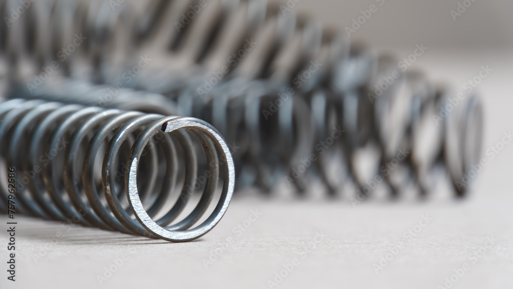 Obraz premium Coiled metal spring on metal surface, close-up view