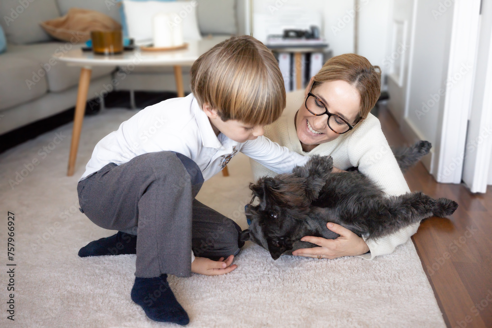Portrait of a happy mother and son at home playing with their dog Portrait of a happy mother and son at home playing with their dog
