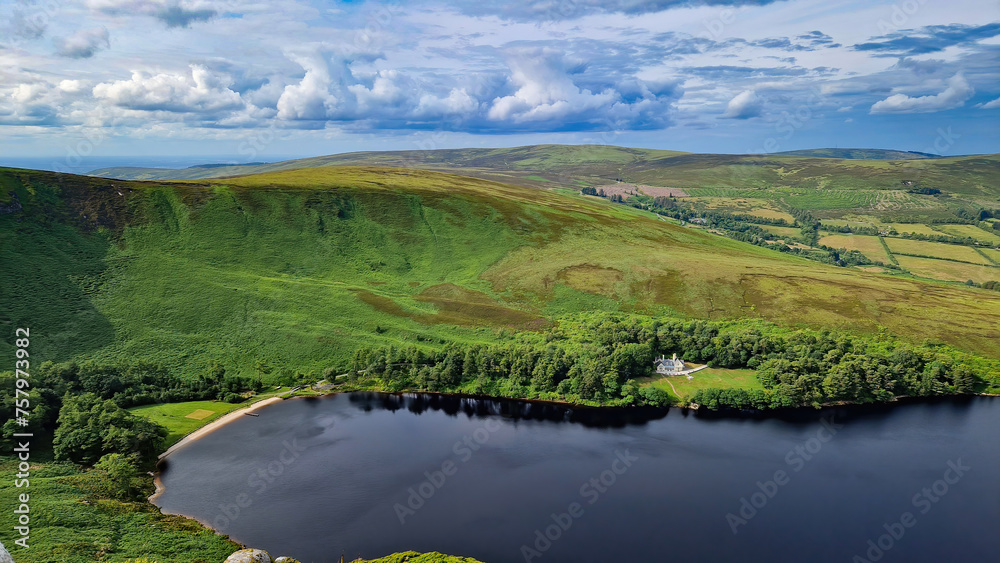 Perched atop the peak, Lough Bray Lower emerges like a sapphire amidst the emerald landscape of the Wicklow Mountains.