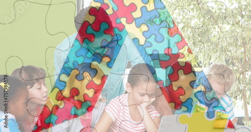 Image of puzzle pieces over diverse schoolchildren and teacher using laptop