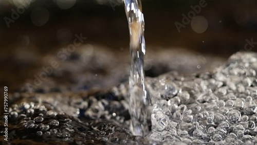 ripresa video rallentata con visuale macro di un flusso d'acqua che cade da un rubinetto all'interno di una grande vasca di legno photo