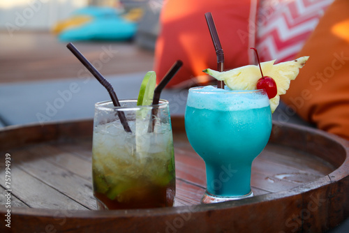 Two cocktail glasses, mojito and swimming pool on a wooden table