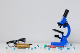 Blue microscope, eyeglasses and pills on table