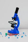 Blue microscope and pills on white table