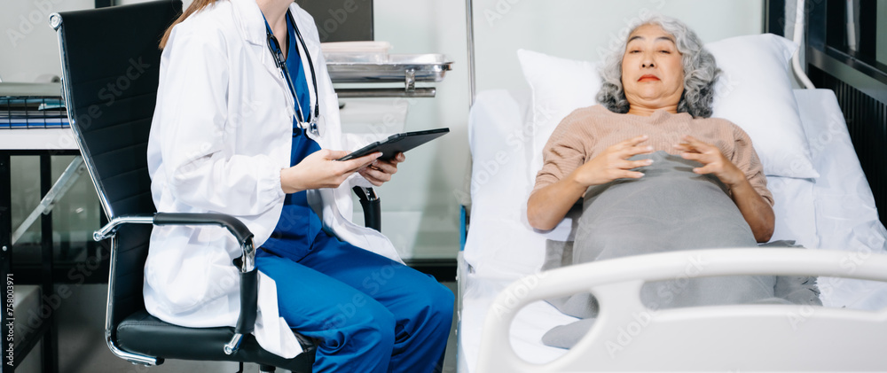 doctor in white suit take notes while discussing and Asian elderly, man patient who lying on bed with receiving saline solution in hospital or clinic.. doctor in white suit take notes while discussing and Asian elderly, man patient who lying on bed with receiving saline solution in hospital or clinic..