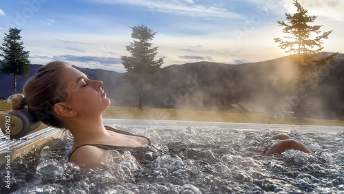 Spa on holidays. Woman relaxing in outdoor hot pool. Mountain view in winter day