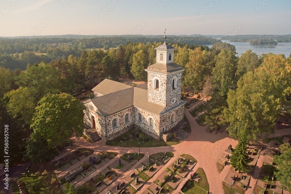 Aerial view of old neoclassical greystone Nummi church with bell tower surrounded with graveyard, Nummi-Pusula, Finland.