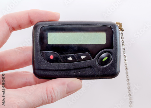 pager in close-up, an old retro communication device, in female hand on a white background photo