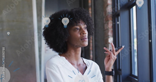 Image of light bulb icons over african american businesswoman in office