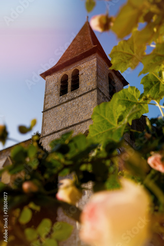 Large angle of church of Monpazier with a rose in the foreground against a blue sky, good living. Dordogne, Nouvelle-Aquitaine photo