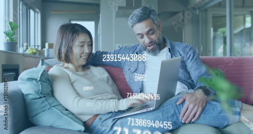 Image of numbers changing over biracial couple using laptop