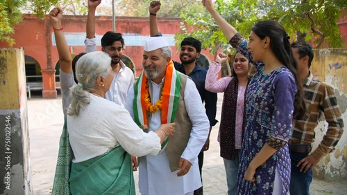An elderly lady putting a tricolour scarf on the political party leader - elections  lok sabha party member  Indian democracy. The supporters of the political party supporting their leader for winn... photo