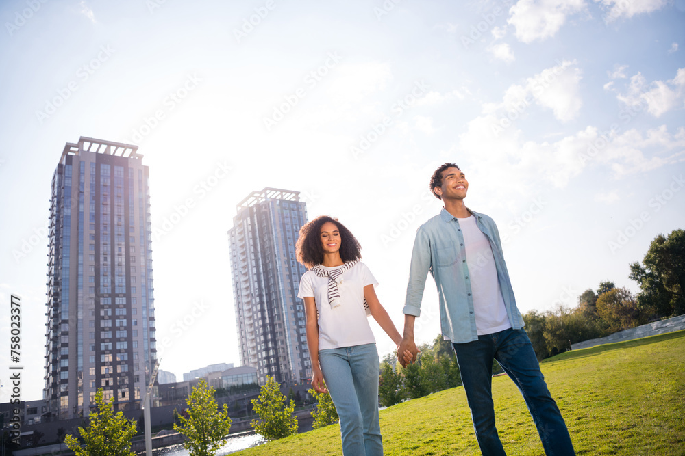 Low angle photo of romantic beautiful young idyllic students couple strolling hands together in park outdoors just bought apartments Low angle photo of romantic beautiful young idyllic students couple strolling hands together in park outdoors just bought apartments