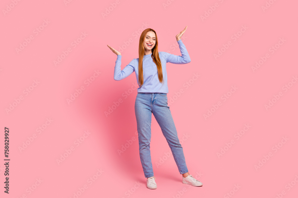 Full size photo of satisfied woman dressed blue shirt jeans raising palms up announcing sale empty space isolated on pink color background Full size photo of satisfied woman dressed blue shirt jeans raising palms up announcing sale empty space isolated on pink color background