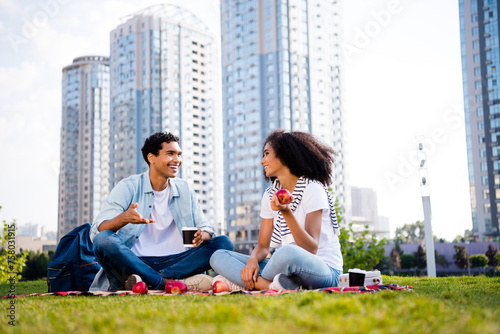 Full size photo of positive partners sitting blanket drink coffee eat apple chatting enjoy free time outside