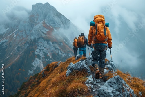 A group of adventurers hikes along a ridge with fog enshrouded peaks in the background, showcasing the beauty of nature