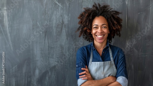 Smiling woman in apron standing on gray background.