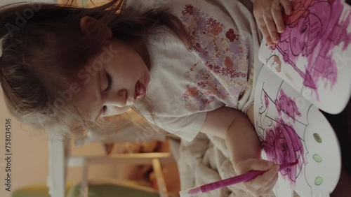 Cute little girl drawing with pink colorful pens while sitting on the floor at home. Educational activities for kids photo