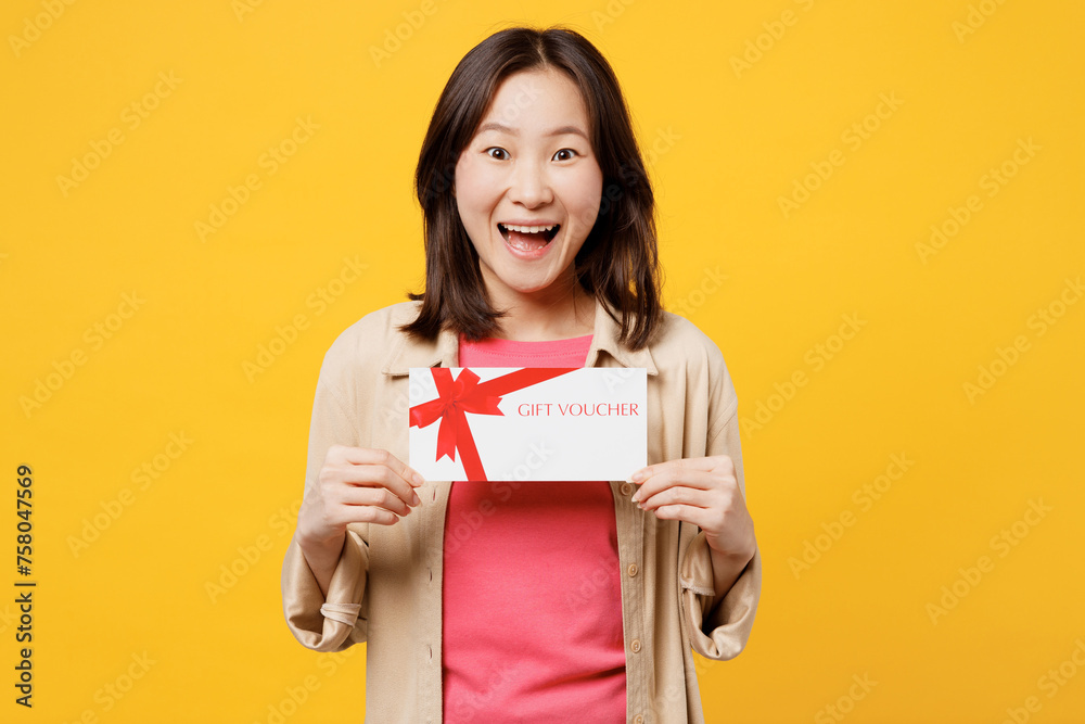 Young surprised woman of Asian ethnicity wear pink t-shirt beige shirt pastel casual clothes hold gift certificate coupon voucher card for store isolated on plain yellow background Lifestyle portrait Young surprised woman of Asian ethnicity wear pink t-shirt beige shirt pastel casual clothes hold gift certificate coupon voucher card for store isolated on plain yellow background Lifestyle portrait