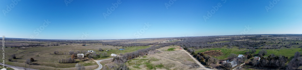 Panoramic aerial view of a rural area with fields and leafless trees