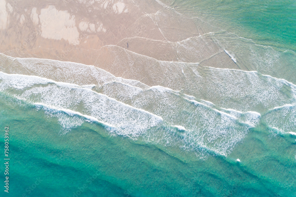 a person walking on the beach in the morning, aerial view from above with a drone.