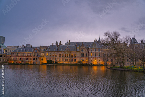The Hague, Netherlands March 22 2023: Binnenhof castle (Dutch Parliament) with the Hofvijver lake against a background of skyscrapers and blue cloudy sky at dusk (Den Haag)