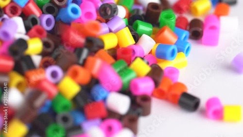 Multicolored beads falling down on white table. Colorful beads background, close up. photo