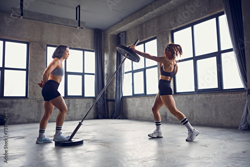 Slika na platnu Focused athlete women doing rotational landmine press exercise in workout space, gym