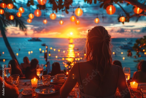 A serene image capturing a woman's back as she watches a breathtaking sunset at a tropical beach resort, surrounded by lit lanterns