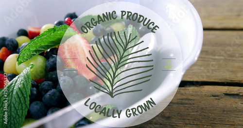 Image of organic produce locally grown text banner over bowl of fruit salad on wooden table