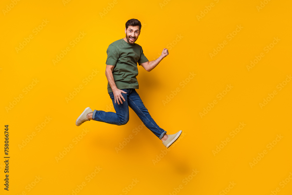 Full body photo of attractive young man jump raise fist celebrate winning wear trendy khaki clothes isolated on yellow color background