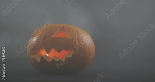 Image of happy halloween text with bat over orange carved pumpkin