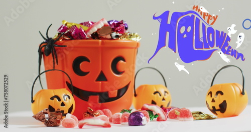 Happy halloween text banner and ghosts icons against pumpkin shaped bucket full of halloween candies