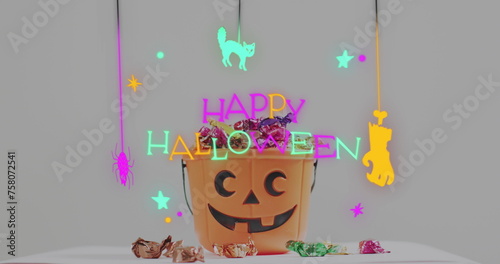 Neon happy halloween text banner against pumpkin shaped bucket full of halloween candies