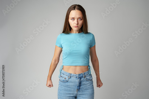 Angry woman standing and arguing with clenched fists on gray background