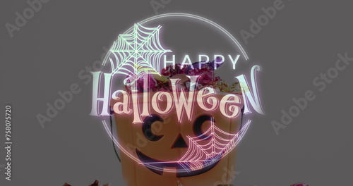 Halloween text banner with spider web icon against pumpkin shaped bucket full of halloween candies