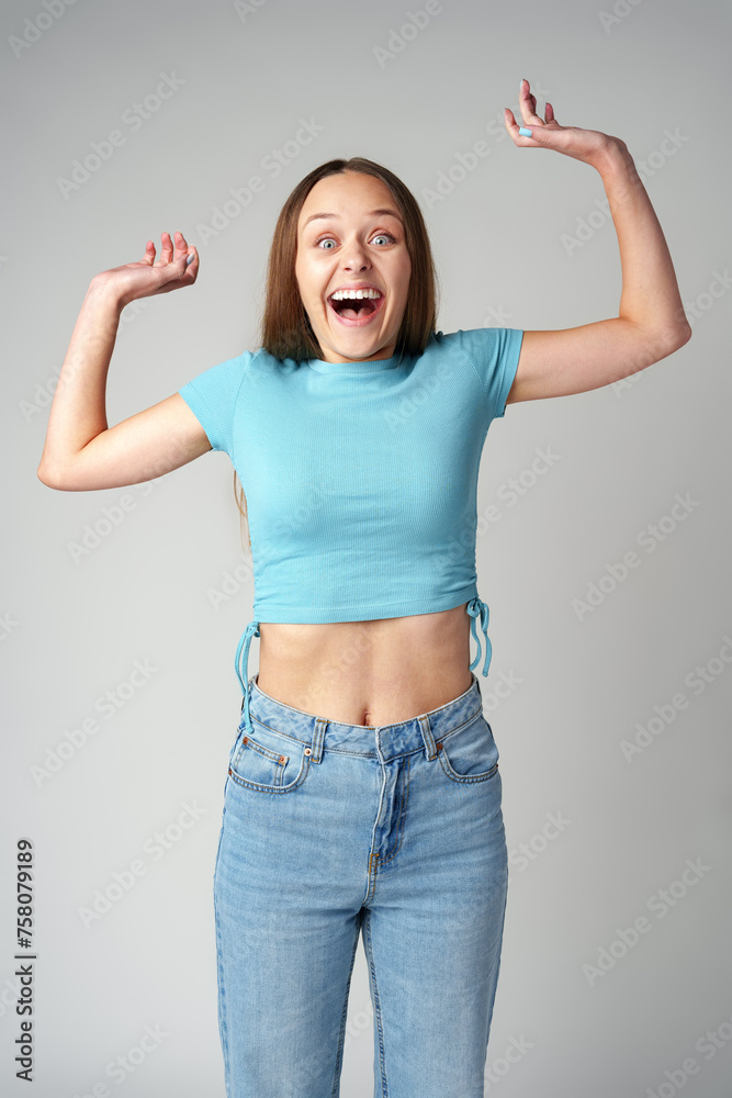 Happy cute young beautiful woman looking excited and surprised on gray background - obrazy, fototapety, plakaty 